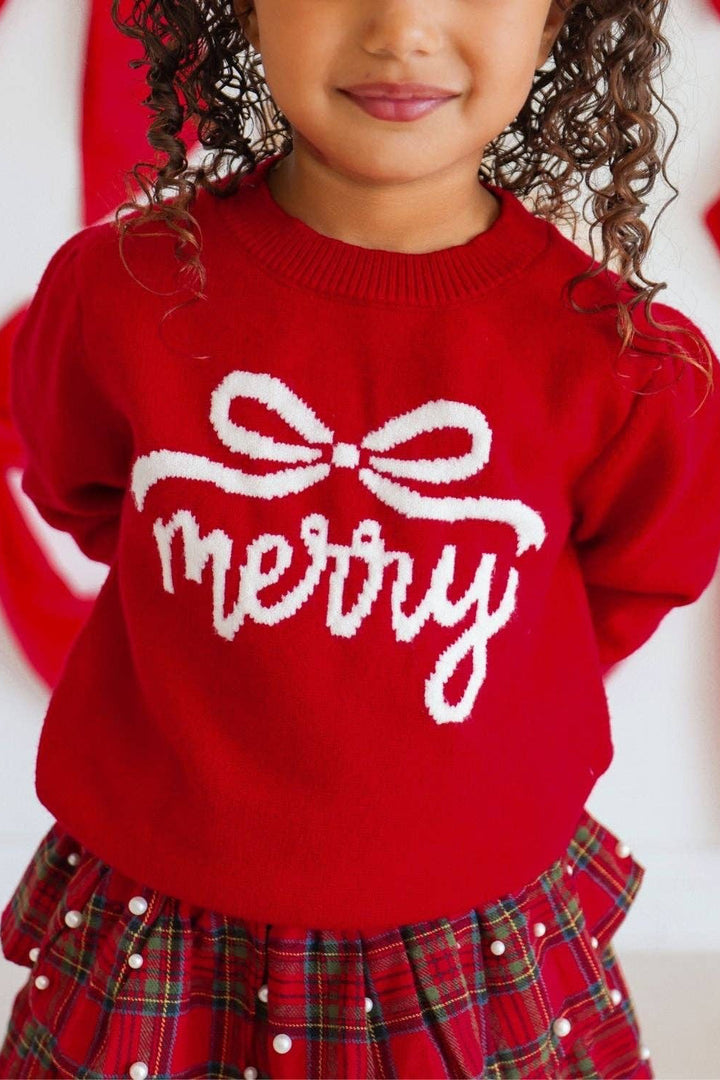A young girl wearing a bright red knit sweater with &
