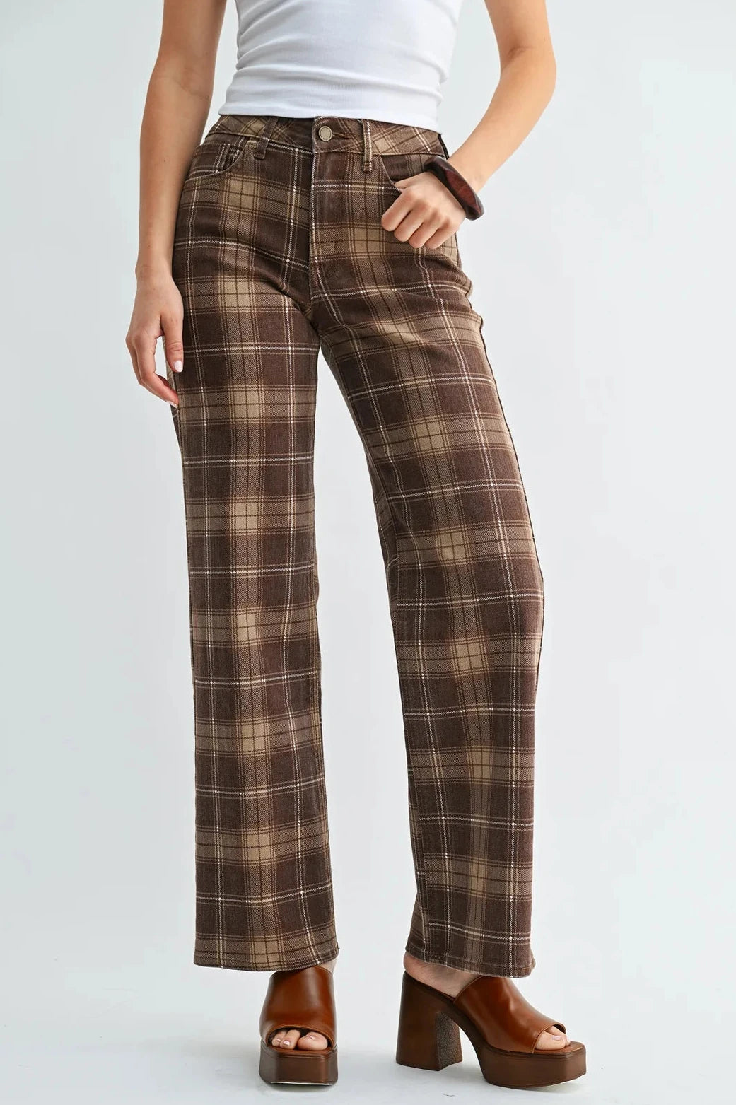 A model wearing brown and beige plaid wide-leg pants, styled with a white tank top and brown platform sandals against a light gray studio background.