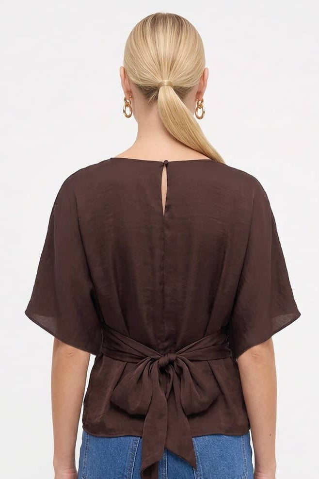 Back view of a brown silky blouse showing the back waist tie detail and keyhole button neckline.